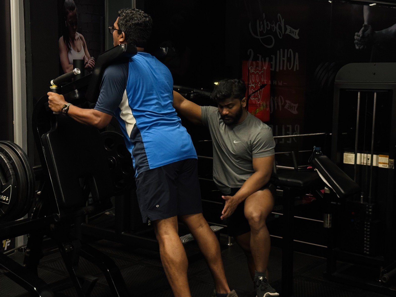 A coach spotting a member mid-set in the strength zone